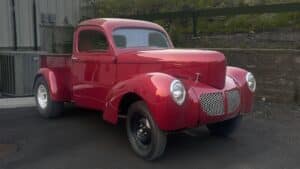 Red 1941 Willys-Overland Model 441 classic pickup truck with a polished wood bed, subject of an ongoing multi-state transit investigation.