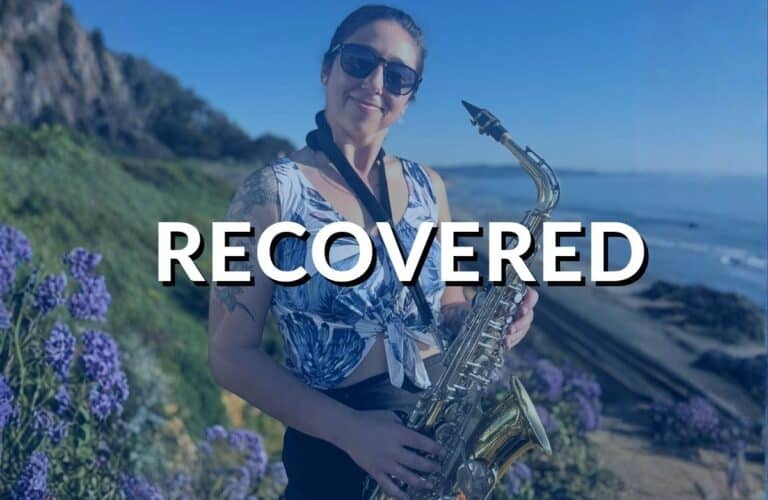 A woman with sunglasses smiling and holding an alto saxophone, which is a Yamaha YAS-23, on a sunny day with purple flowers in the background, labeled 'RECOVERED'. The saxophone had been previously listed as stolen.