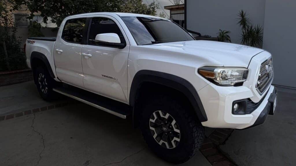 White 2017 Toyota Tacoma Off-Road 4x4 truck with black tonneau cover, tinted windows, and side steps.